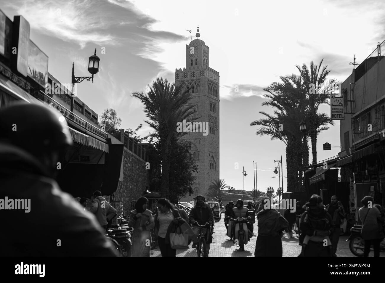 Scena di strada vicino alla moschea di Koutoubia, Marrakech. Minareto storico, palme, vivace vita di strada. Foto Stock
