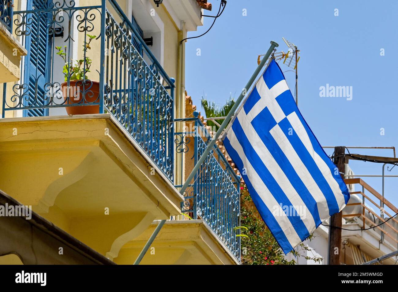 AEGINA, Grecia - Maggio 2022: Bandiera nazionale greca che vola dal balcone di una casa in città Foto Stock