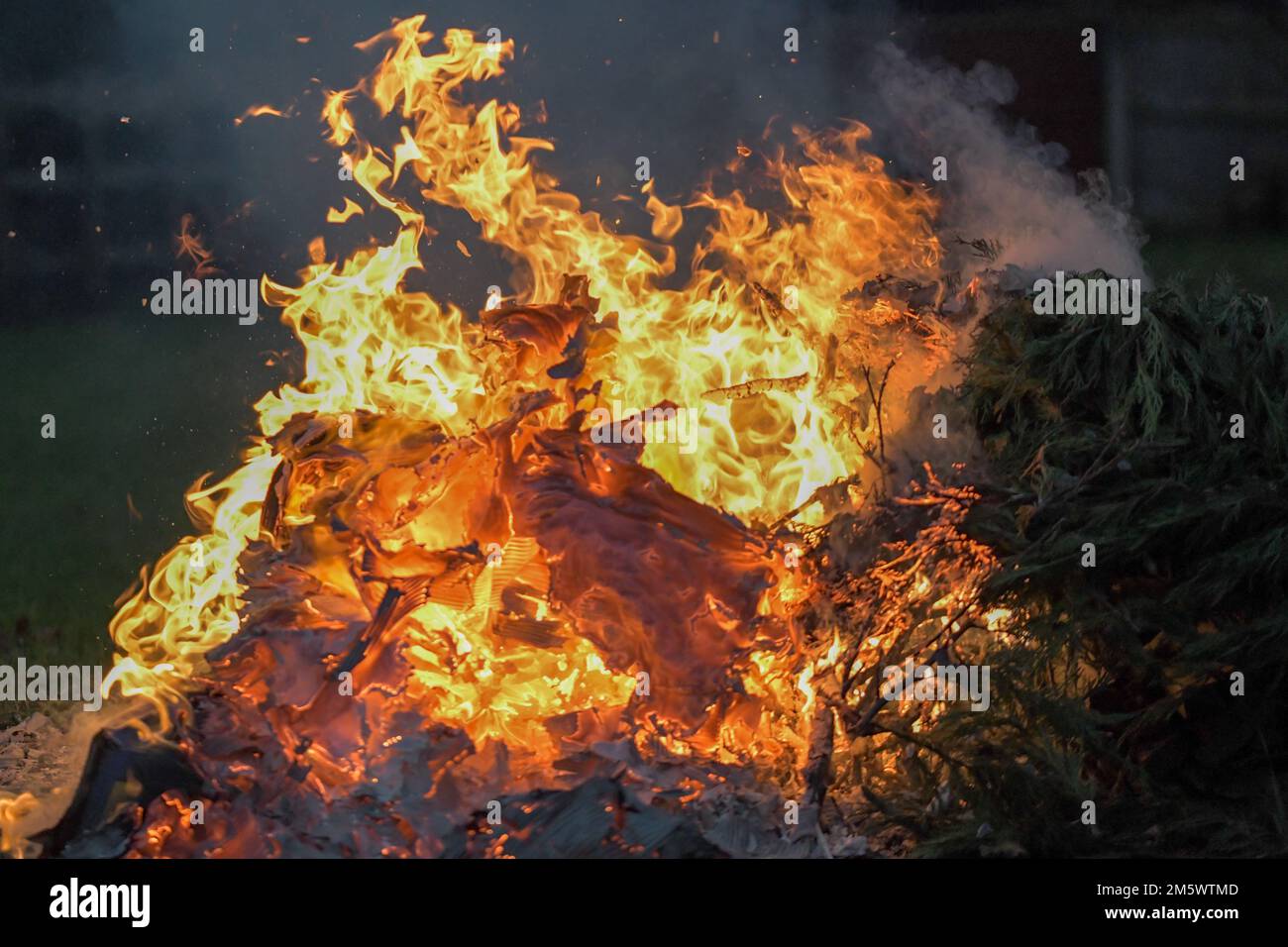 Un fuoco ardente con fiamme profonde arancioni e gialle, falò da giardino Foto Stock
