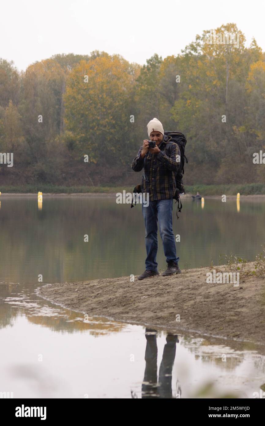 Ritratto di un viaggiatore al lago in autunno scattando una foto con la fotocamera digitale. Foto di alta qualità Foto Stock