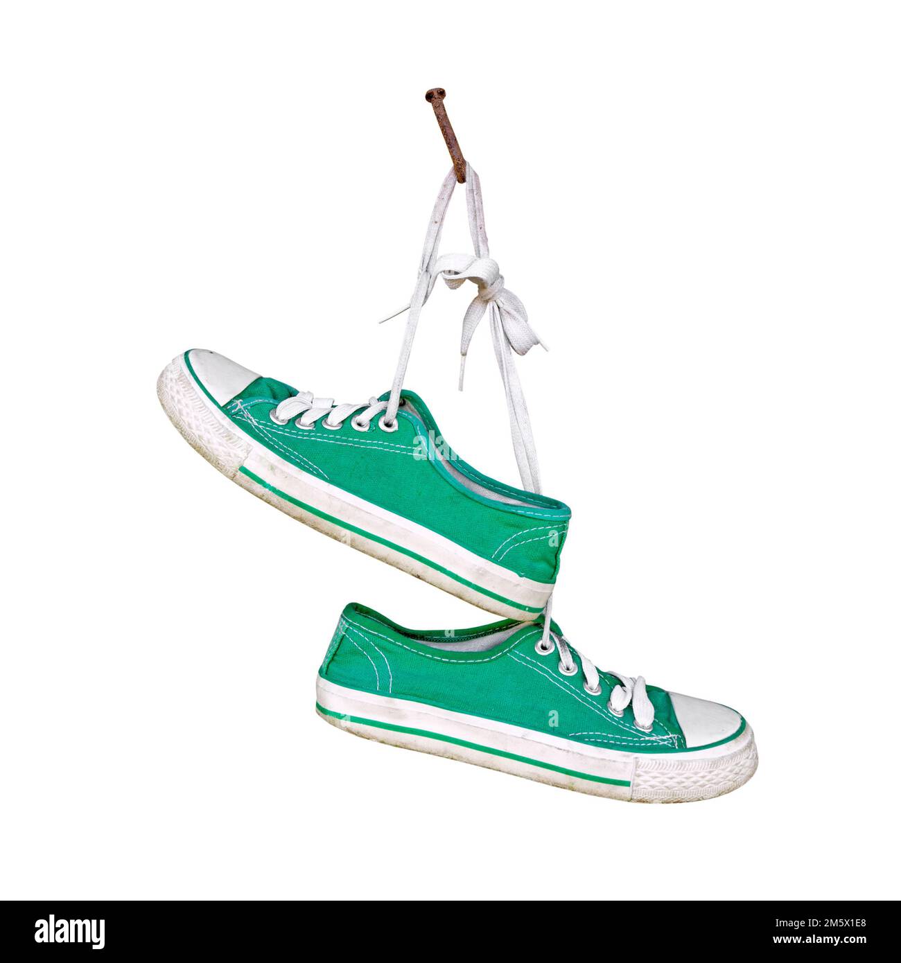 Paio di vecchie sneakers verdi appese su un chiodo rustico isolato su sfondo bianco Foto Stock