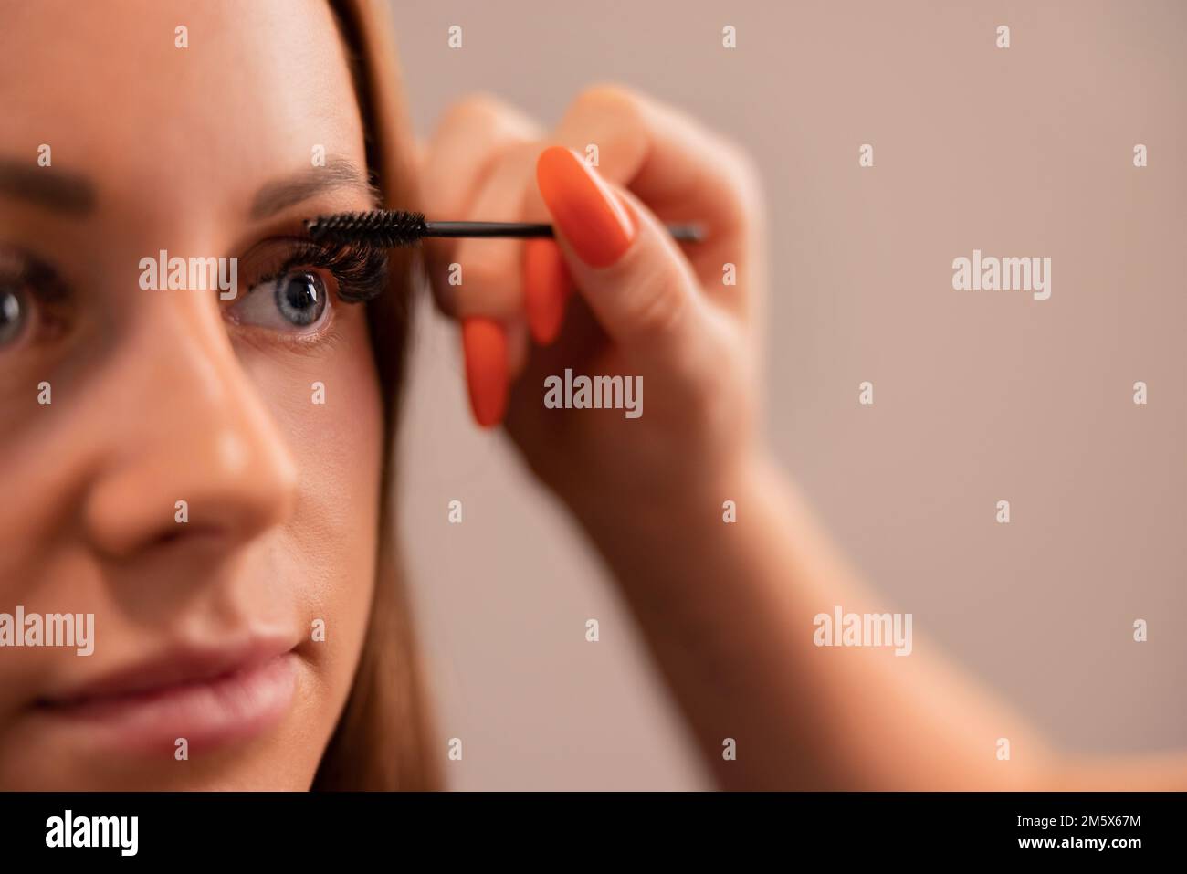 Mano di Specialista che utilizza Mascara sulle ciglia false del cliente Foto Stock