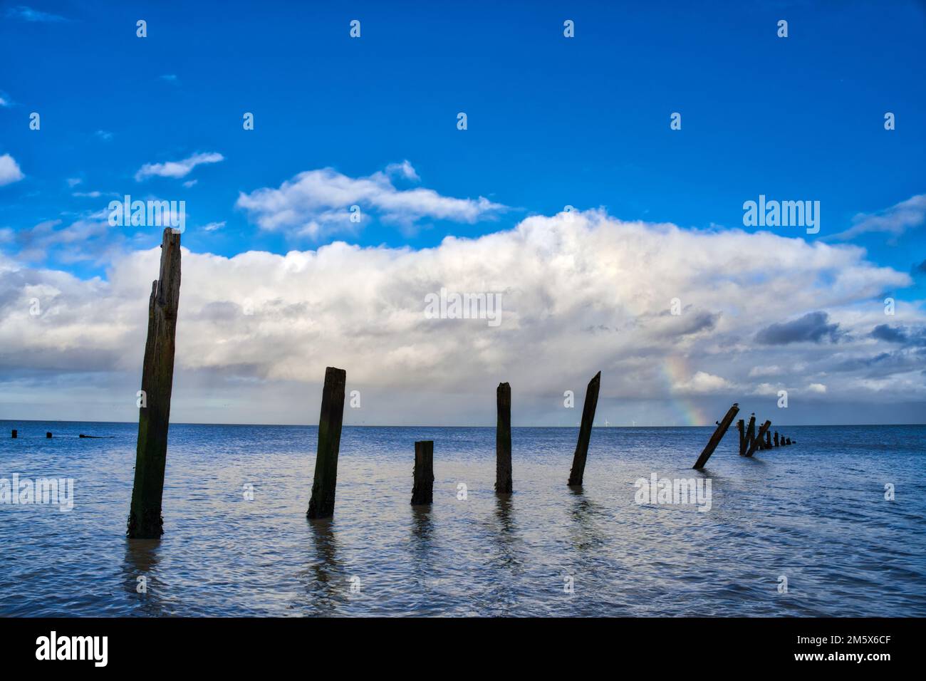 Nuvola bianca che si forma sotto il cielo blu con arcobaleno nella distanza mare fronte Kent Inghilterra UK Foto Stock