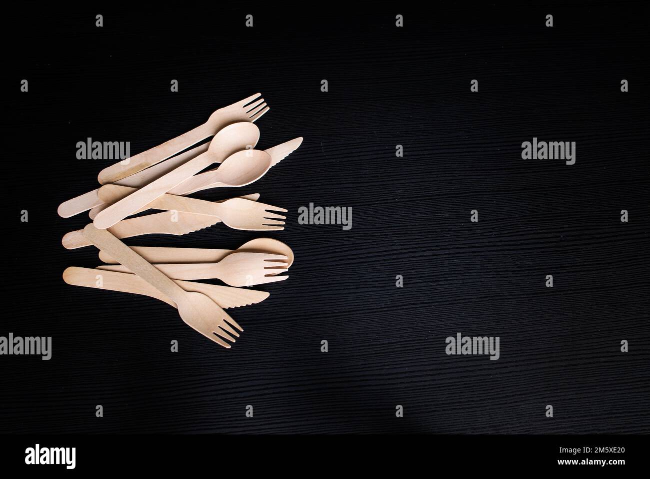 cucchiai, forchette e coltelli in legno ecologici monouso su sfondo scuro Foto Stock