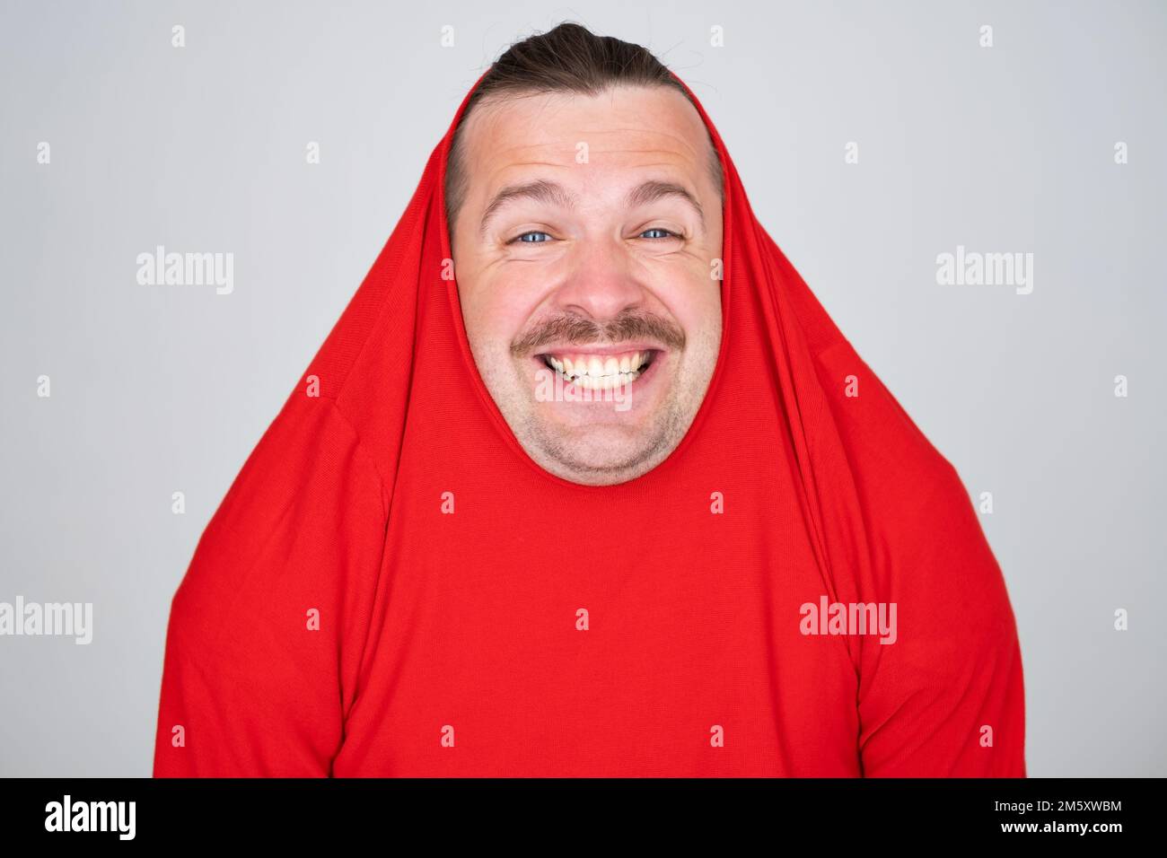 Divertente uomo caucasico coprendo la testa con maglione sorridente allegro e divertente. Foto Stock