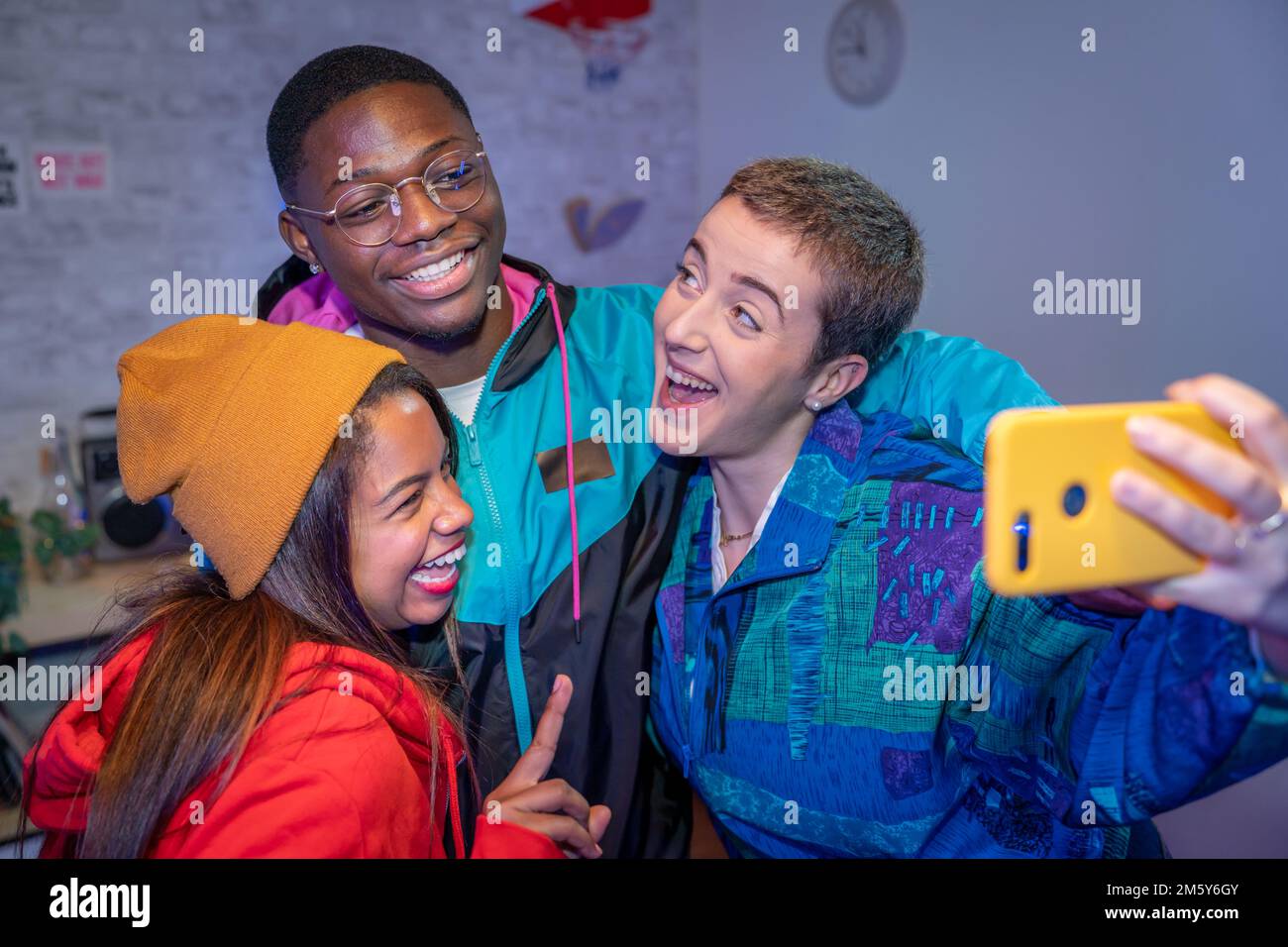 Amici adolescenti multietnici che scattano foto selfie con flash non filtrato. Riprese notturne in interni. Foto Stock
