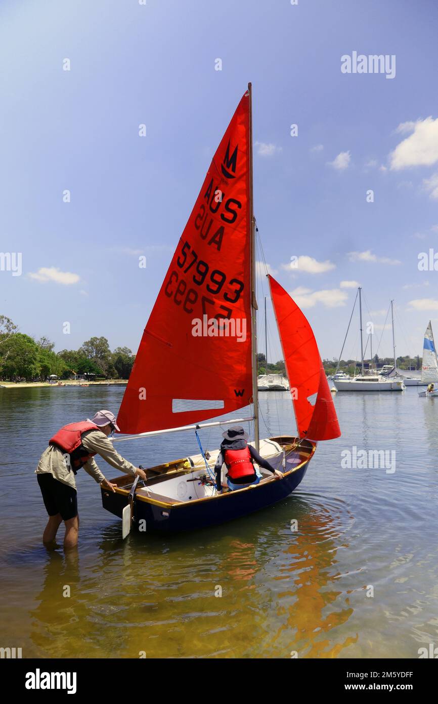 Padre e figlio che si affacciano su Mirror Sailing Dinghy con vele rosse, Matilda Bay, Swan River, Perth, Australia Occidentale. No MR o PR Foto Stock