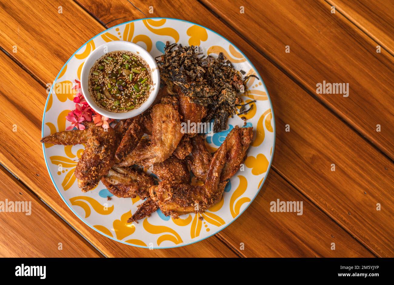 Ali di pollo fritte con erbe, cibo tradizionale tailandese ali di pollo fritte con salsa piccante su tavolo di legno, vista dall'alto cibo immagine. Foto Stock