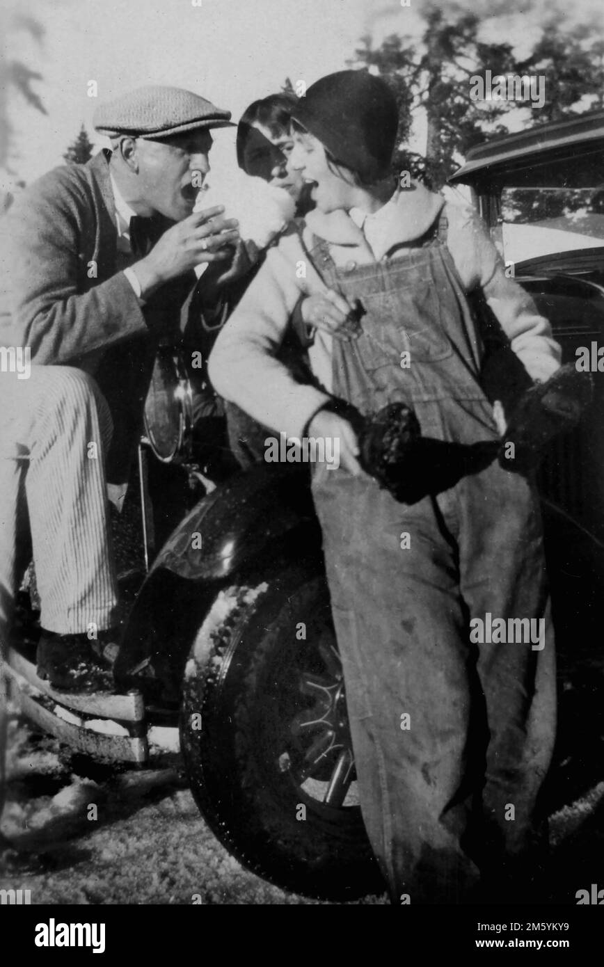 Giovane coppia posa elegante mentre viaggia attraverso l'ovest americano fingendo di mangiare una palla di neve, ca. 1925. Foto Stock