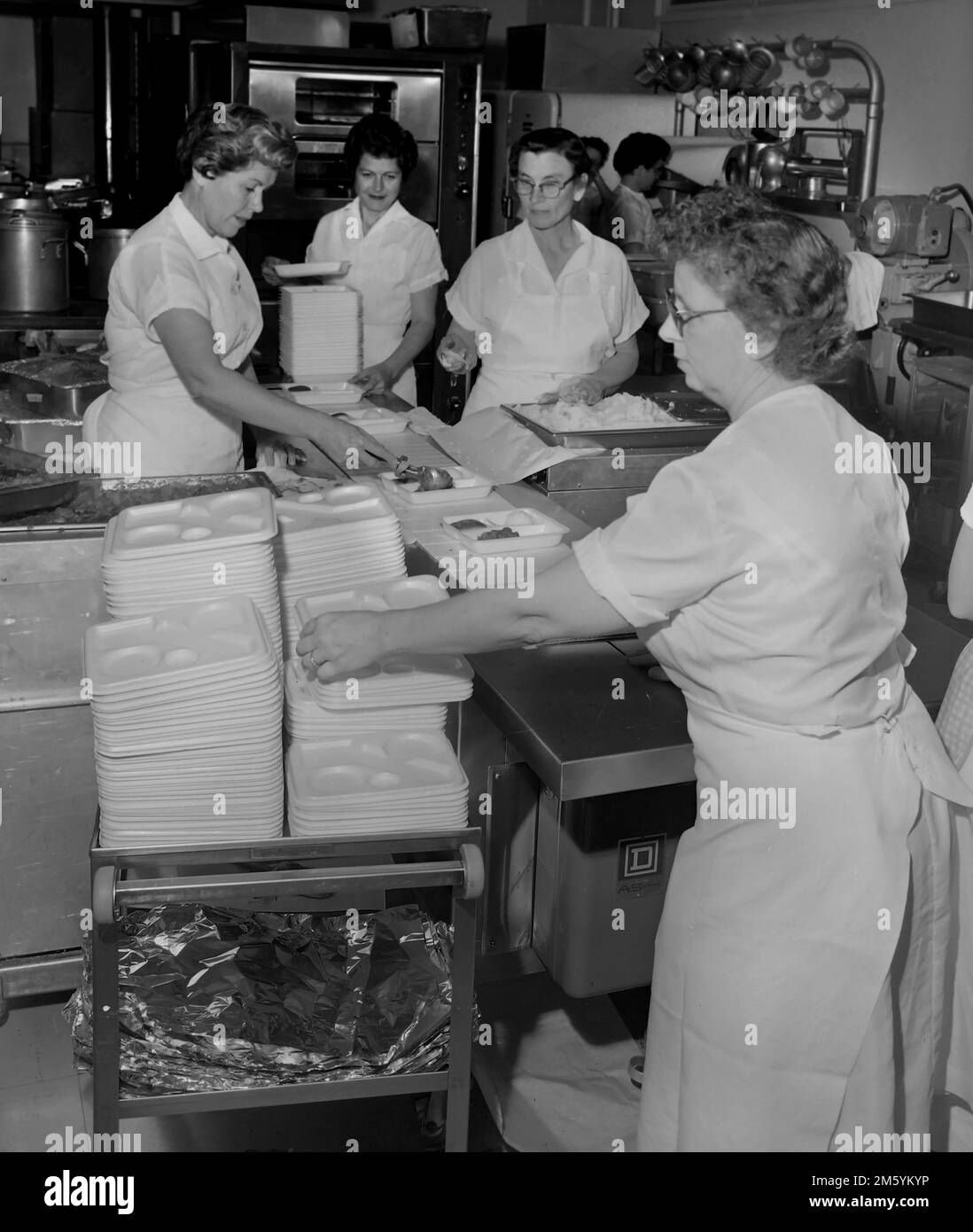 Pranzo le Signore preparano i pranzi in una caffetteria della scuola in California, ca. 1961. Foto Stock