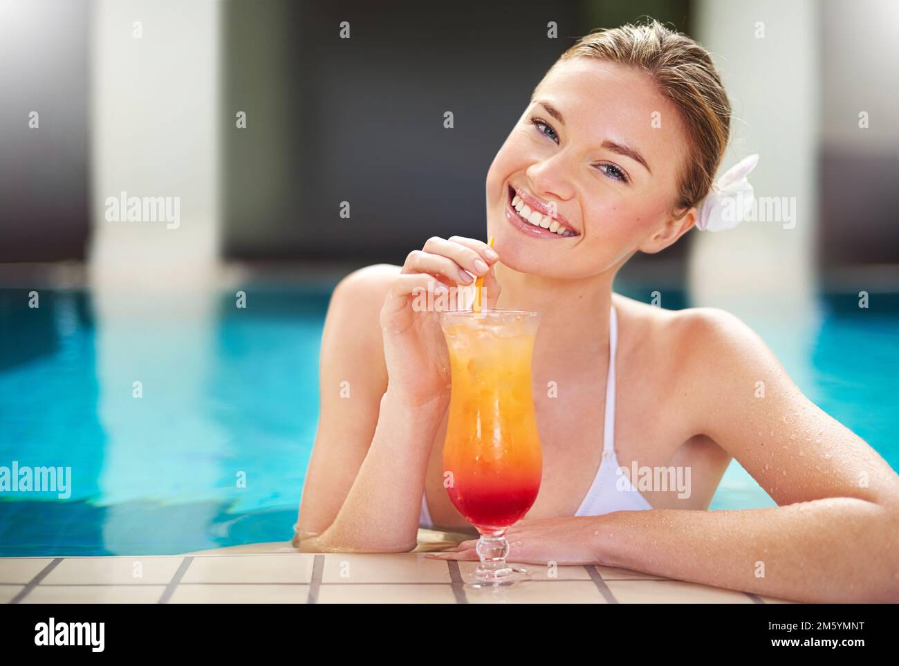 Piaceri poolish. Ritratto di una giovane donna attraente sorseggiando un cocktail in piscina. Foto Stock