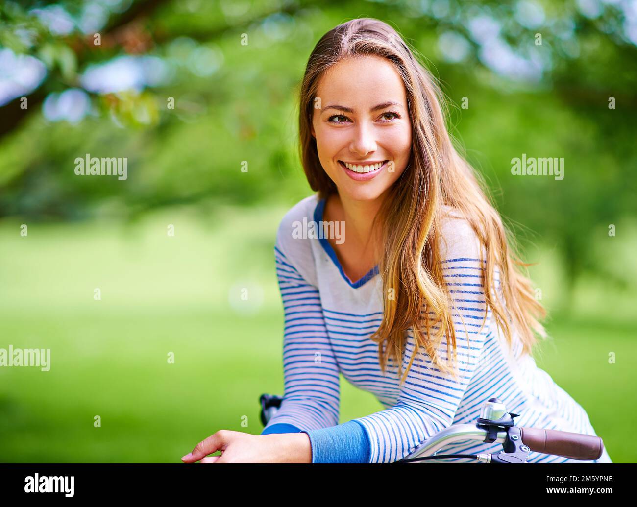 Bella giornata all'aperto. Ritratto di una giovane donna in bicicletta nel parco. Foto Stock