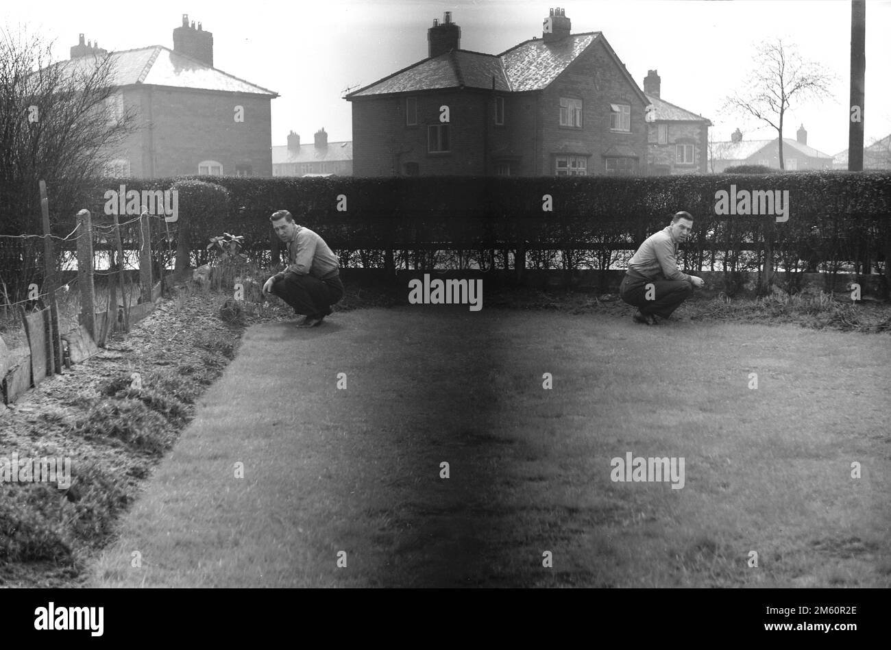 Anni '1950, fotografia storica, amatoriale, un'immagine che mostra una doppia esposizione, un uomo o due uomini inginocchiati in un giardino sul retro, Inghilterra, Regno Unito. Foto Stock