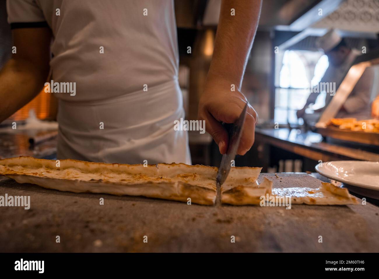 Lo chef taglia il pide di formaggio turco a fette sul tavolo del ristorante Foto Stock