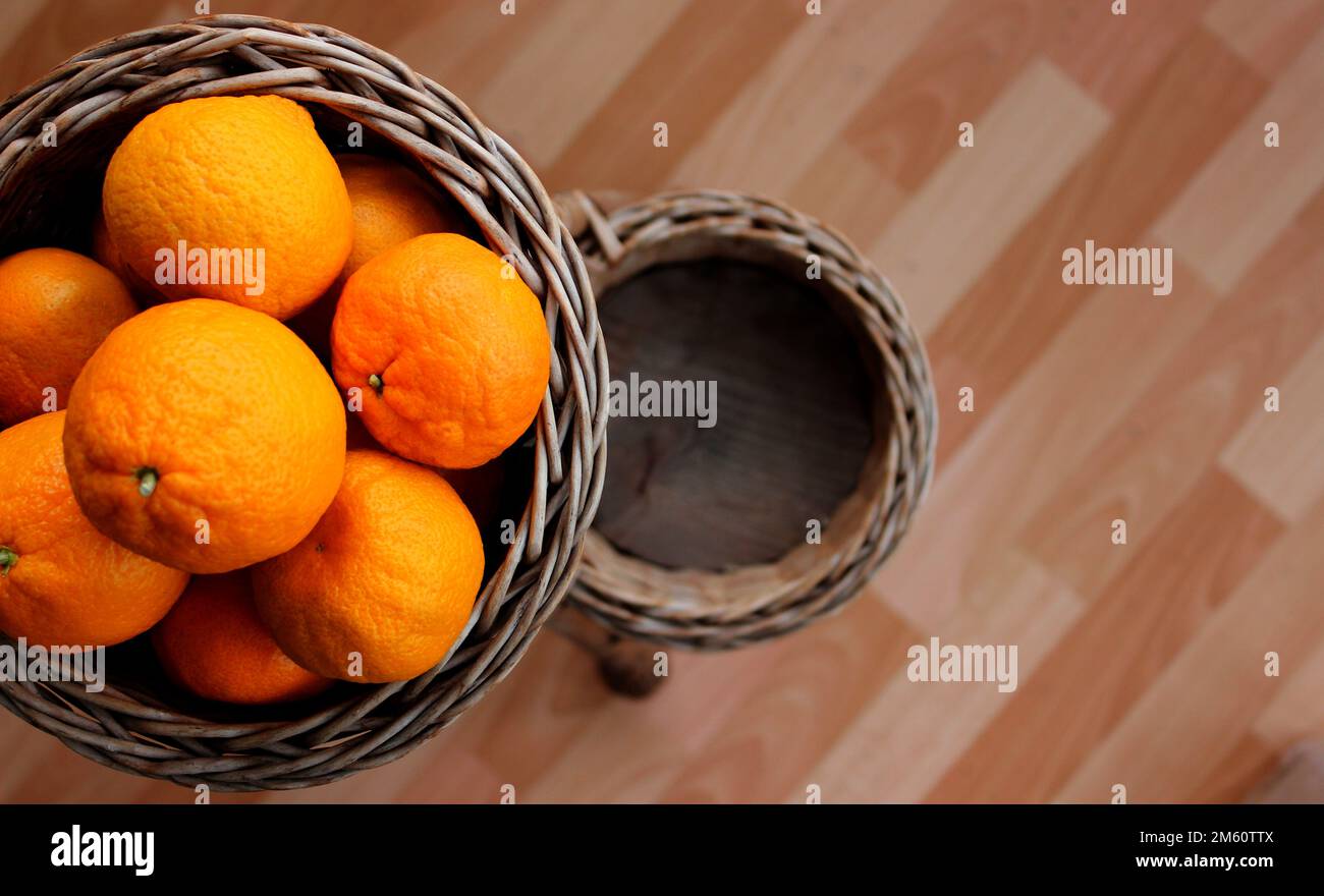 Tangerini arancioni maturi in un cestino di vimini sul lato della foto. Foto concettuale per sfondo o sfondo Foto Stock