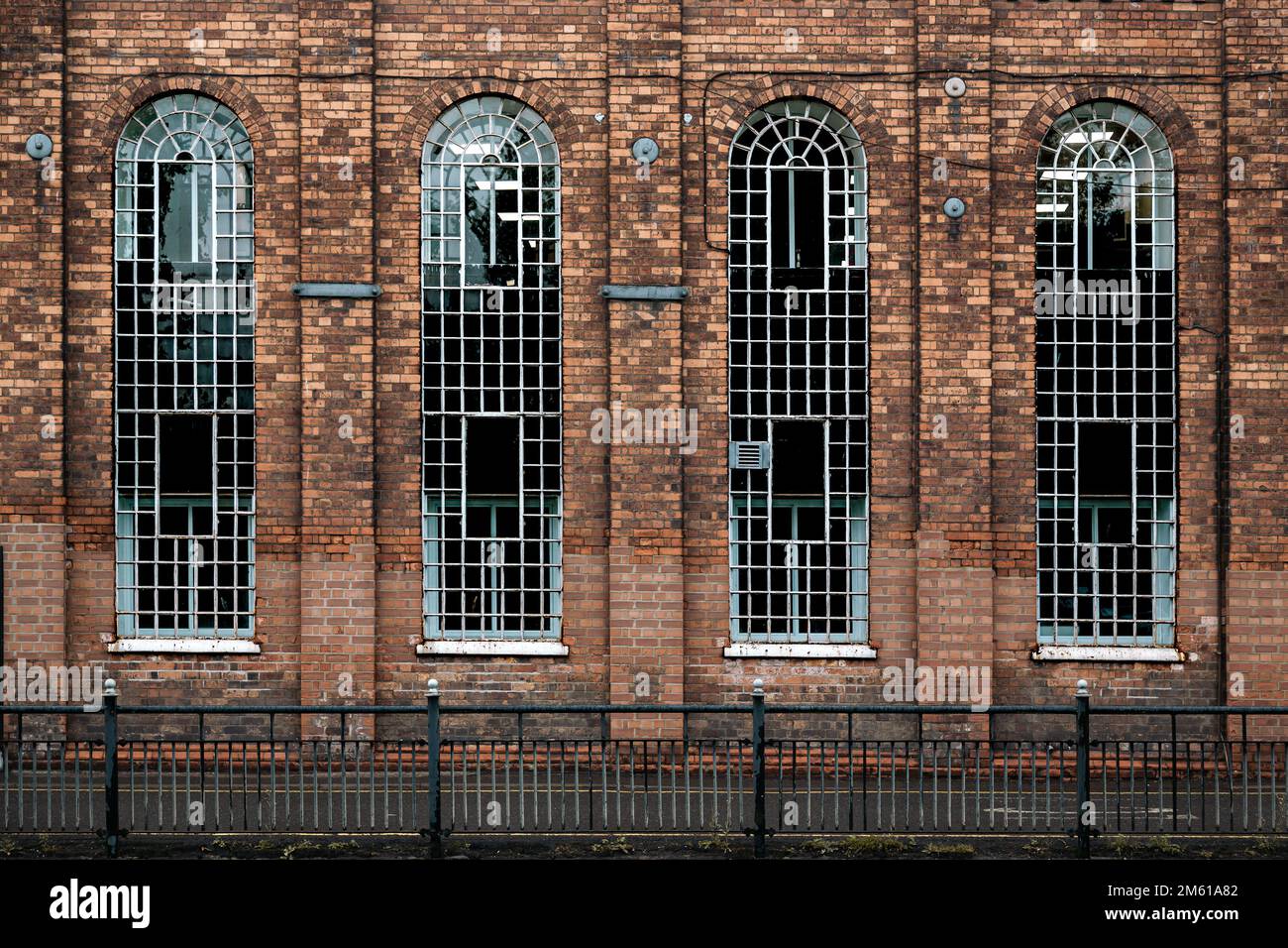 Particolare di alcuni vecchi edifici industriali con alte finestre ad arco. Ingegneria, locali commerciali, officina, concetto di settore. Foto Stock
