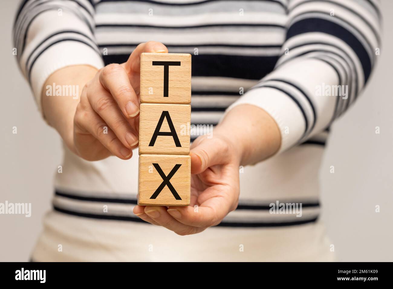 Regolamento FISCALE, calcolo annuale del reddito e del reddito personale, concetto, Donna tiene blocchi di legno con la parola tassa nelle sue mani Foto Stock