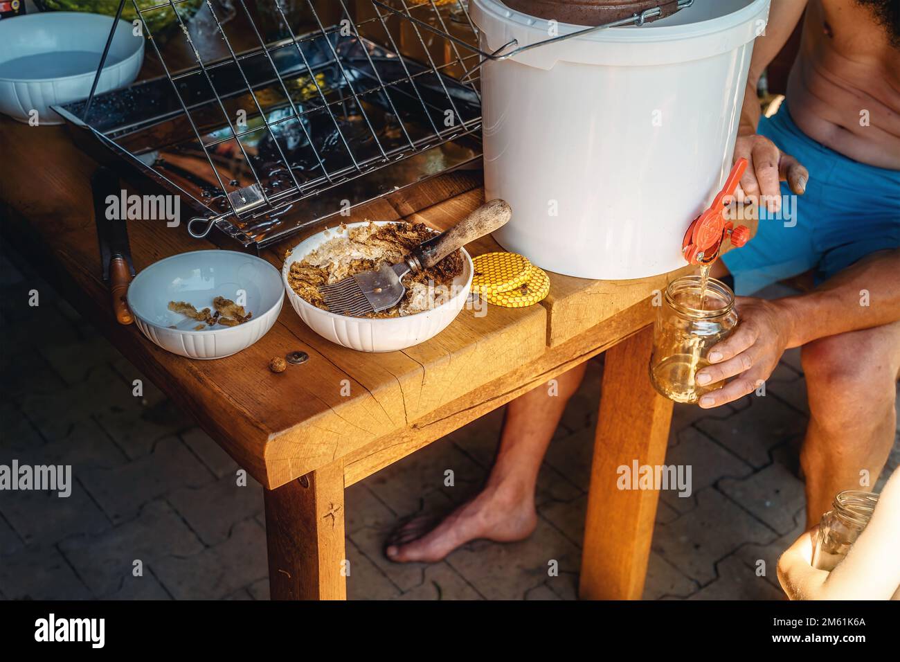 Ottenere il miele da honeycomb. Immagazzinare miele in una bottiglia. Foto Stock