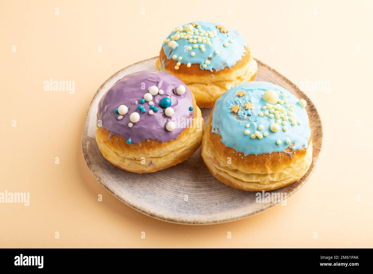 Ciambella smaltata viola e blu su sfondo pastello arancione. vista laterale. Colazione, mattina, concetto. Foto Stock