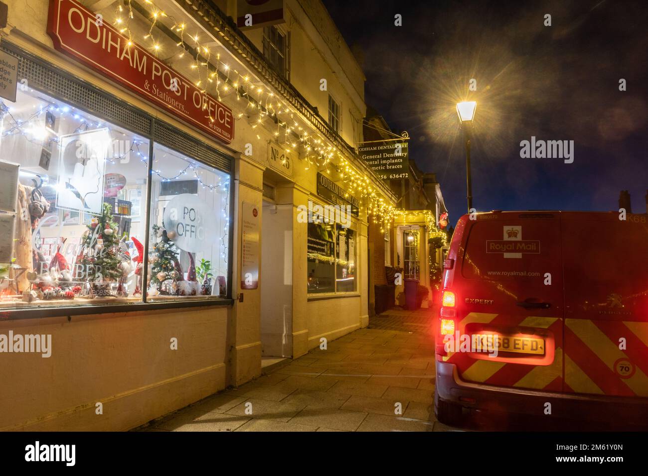 Royal mail van parcheggiato fuori Odiham Post Office al crepuscolo nel dicembre 2022, Hampshire, Inghilterra, Regno Unito, con luci di Natale e lampione stradale Foto Stock