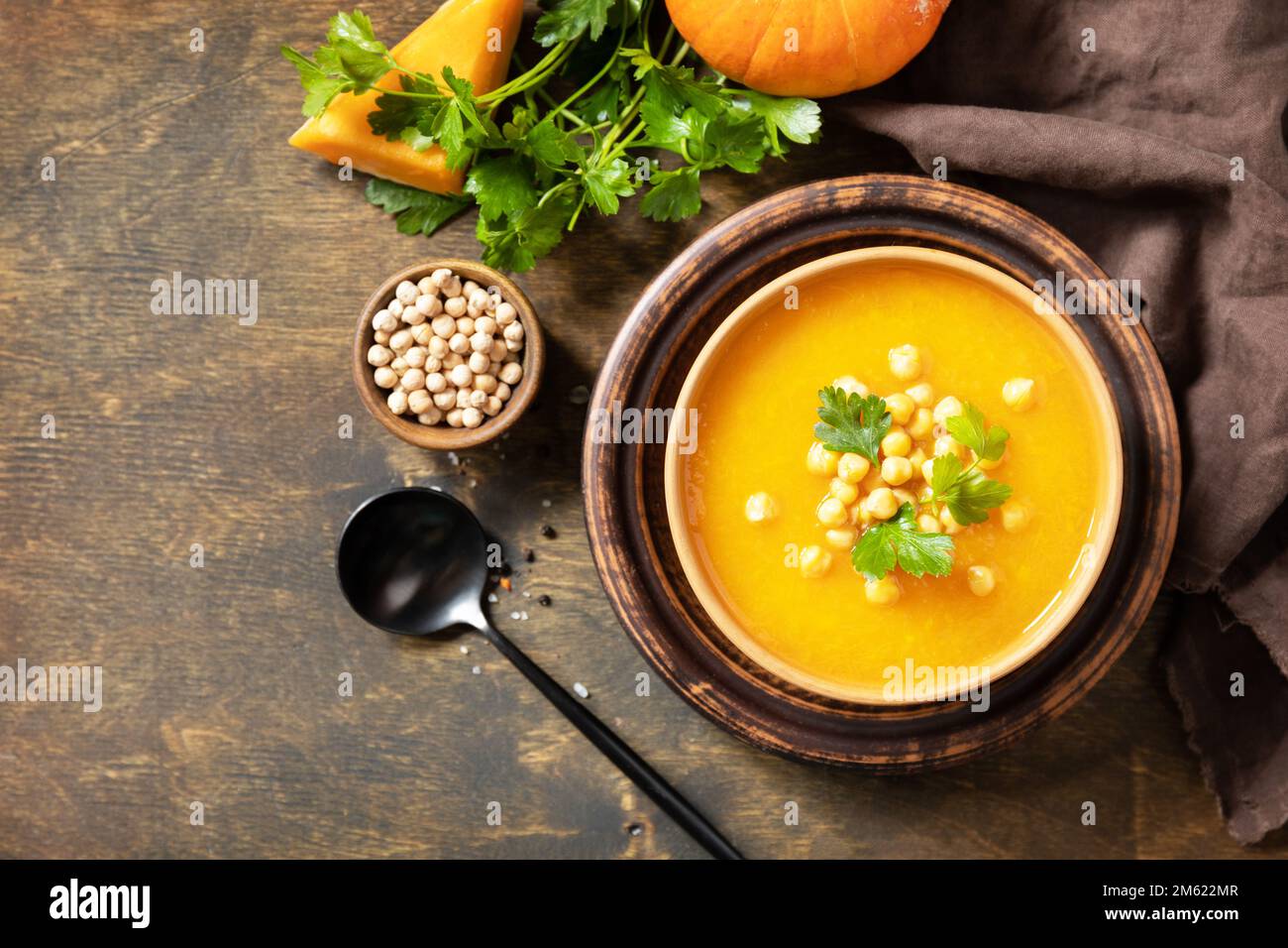 Comfort cibo, autunno e inverno sano slow food concetto. Zuppa vegetariana alla crema di zucca e ceci su un tavolo rustico in legno. Vista dall'alto. Copia sp Foto Stock