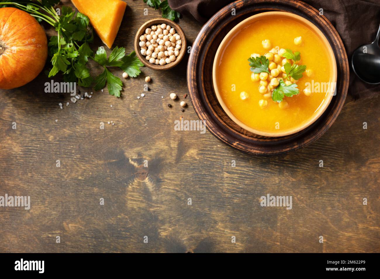 Comfort cibo, autunno e inverno sano slow food concetto. Zuppa vegetariana alla crema di zucca e ceci su un tavolo rustico in legno. Vista dall'alto. Copia sp Foto Stock