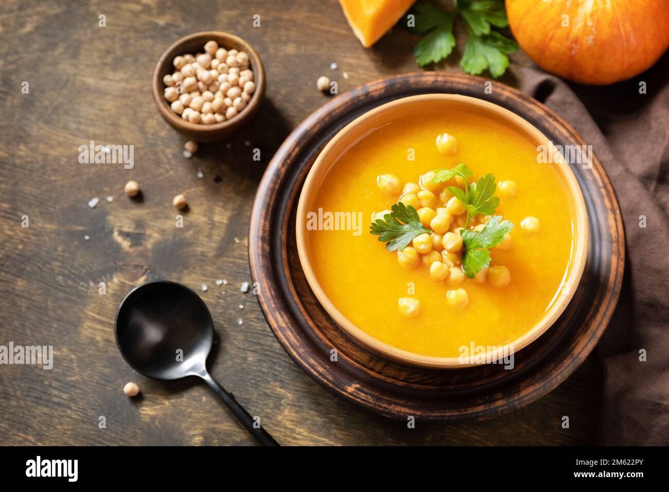 Zuppa vegetariana alla crema di zucca e ceci su un tavolo rustico in legno. Comfort cibo, autunno e inverno sano slow food concetto. Spazio di copia. Foto Stock