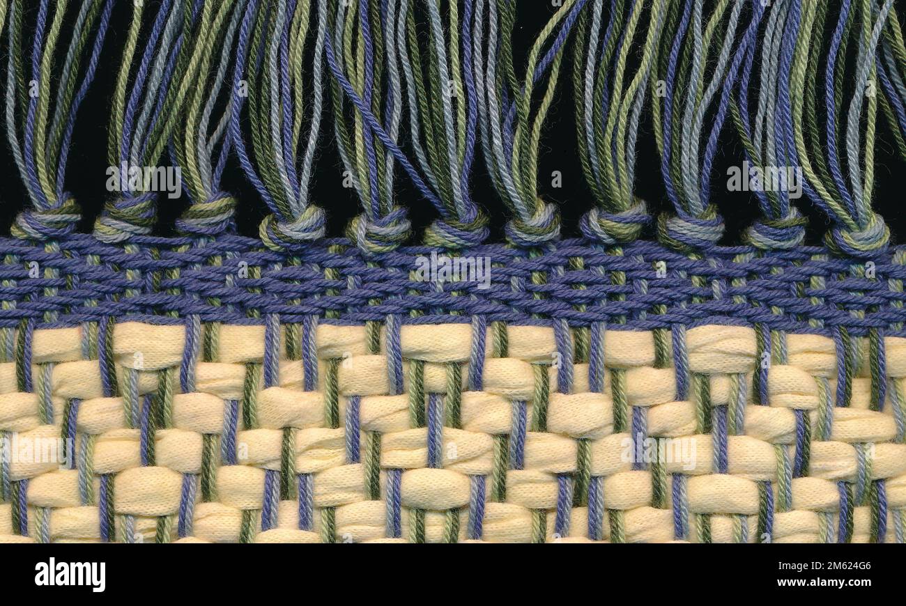 Primo piano di chiusura con frange di tappeti su tappeto di straccio intrecciato a mano. Foto Stock