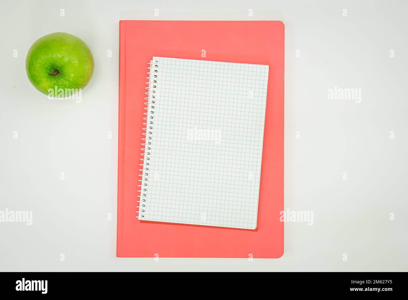 Quaderno a scacchi, blocco note e mela, piatto. Foto Stock