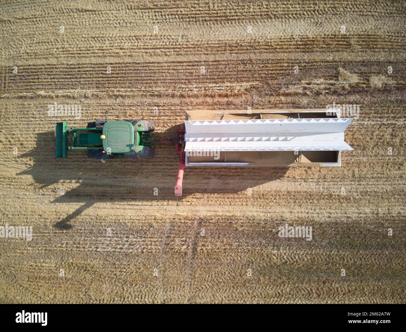 Vista aerea del campo di grano dell'Australia che mostra l'attrezzatura agricola che include un trattore e un contenitore per la raccolta del grano. Victoria, Australia. Foto Stock