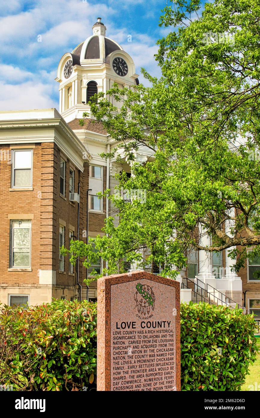 Il tribunale della contea di Love si erge dietro un simbolo storico della contea di Love nel centro di Marietta, Oklahoma. Foto Stock