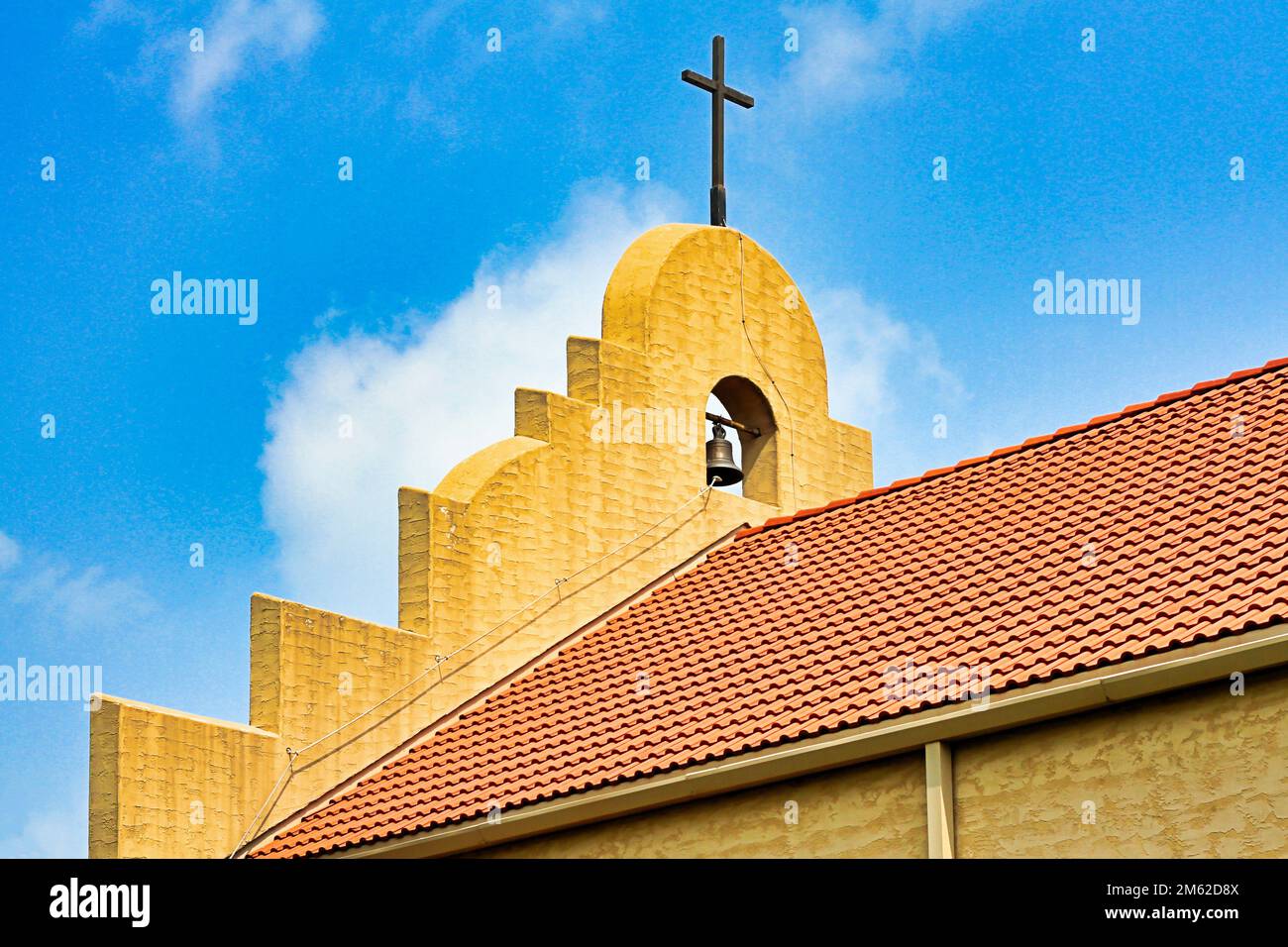 Una vista ravvicinata della croce, della campana e della facciata sul tetto di tegole rosse della Missione Cattolica del buon Pastore a Marietta Oklahoma. Foto Stock