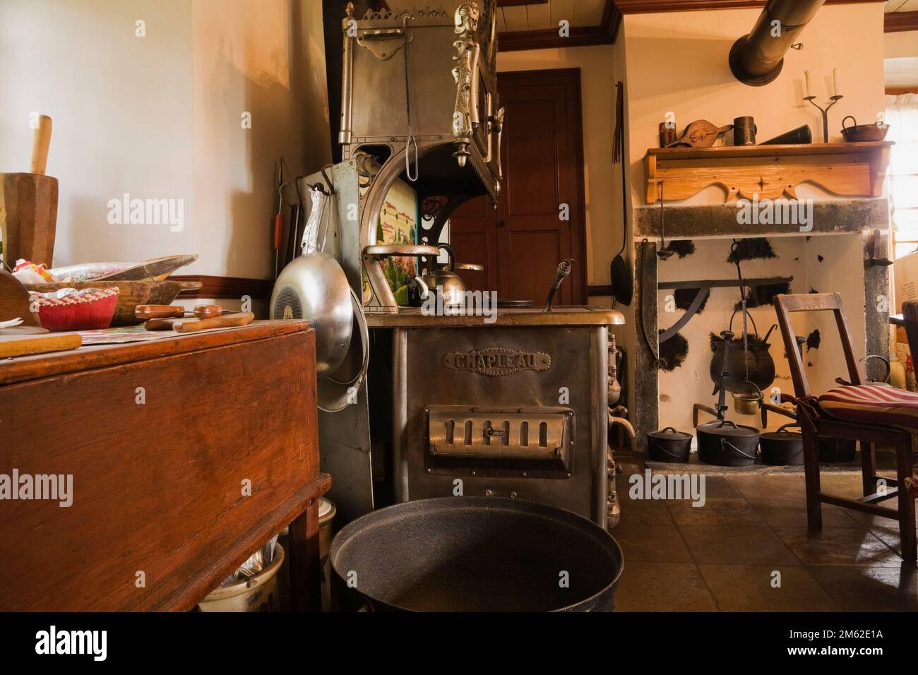 Tavolo da taglio in legno e fornello Chapleau in ghisa antica in cucina all'interno di una vecchia casa di pietra canadesi del 1838. Foto Stock