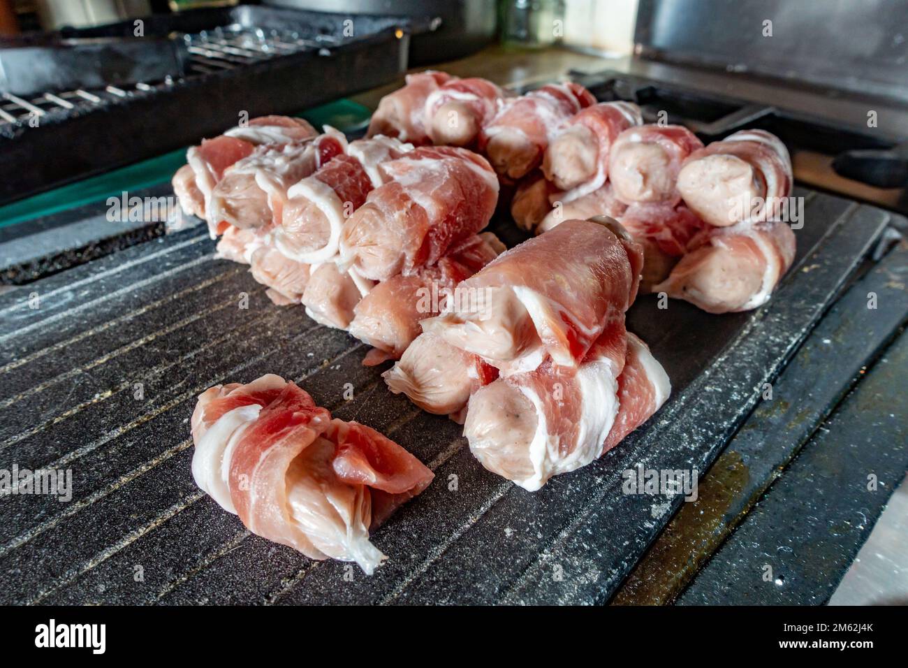 Salsiccia congelata avvolta in pancetta o maiali in coperte scongelanti pronti per cucinare Foto Stock