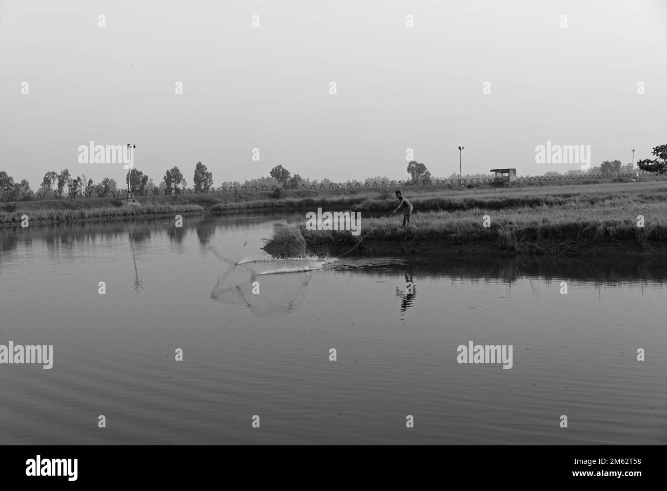 13.11.2022. bengala occidentale. india. Un pescatore indiano solitario che pesca con la rete in stagno naturale. Foto Stock