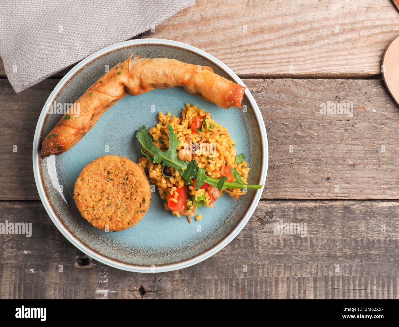 Gustoso Falafel con bulgur piccante e un rotolo di pasta vegetariano su un piatto di ceramica, tradizionale cibo caldo, vista dall'alto Foto Stock