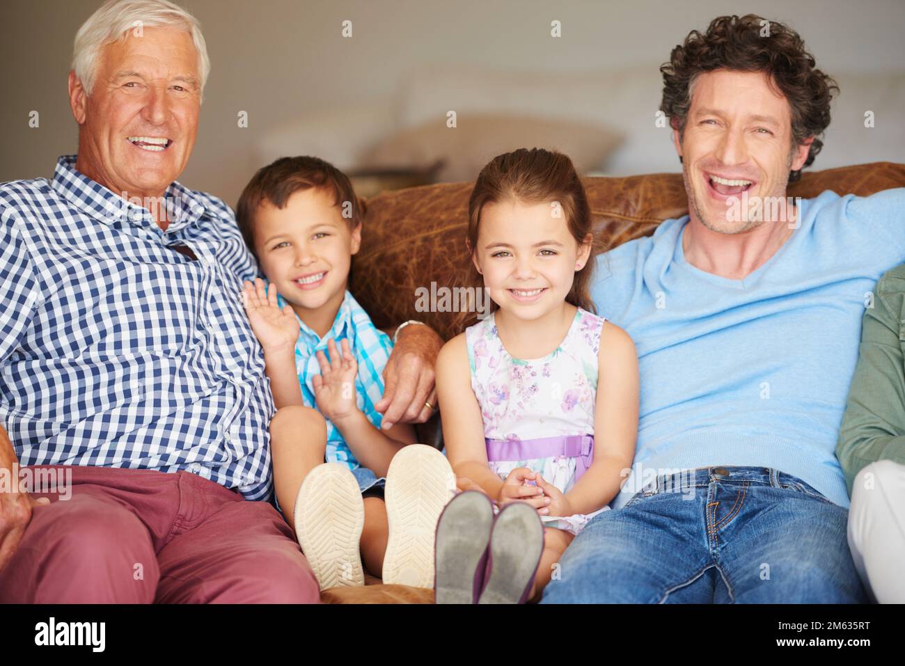 Momenti di famiglia amati. due bambini seduti con il padre e il nonno al coperto. Foto Stock