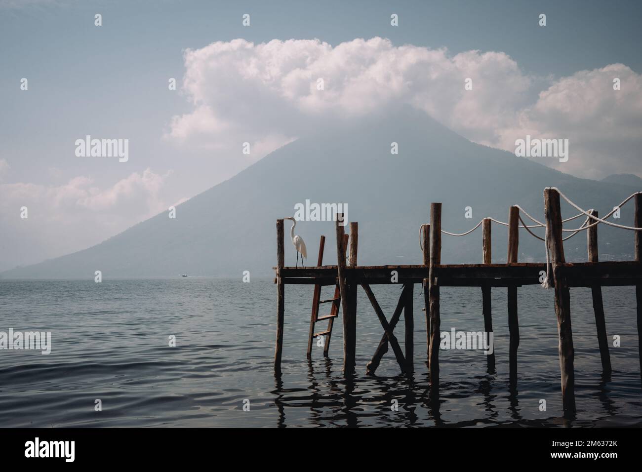 Vecchio molo di legno nel lago Atitlan increspato vicino alla montagna Sierra Madre contro cielo nuvoloso blu in una giornata di sole in Guatemala Foto Stock