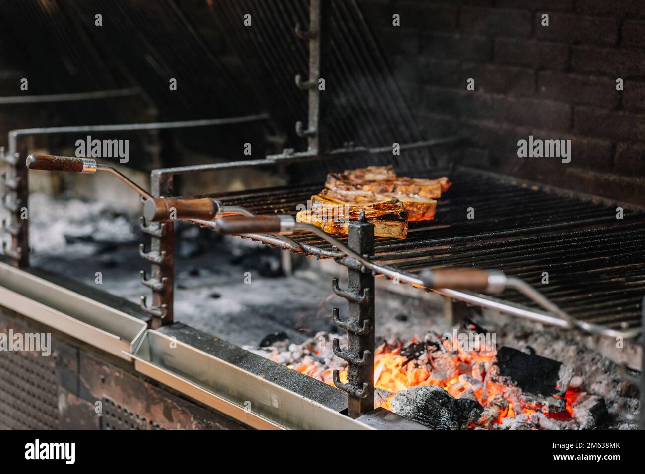 Appetitose bistecche succose poste sulla griglia del barbecue sopra la fiamma bruciante mentre friggete nel forno della griglia Foto Stock