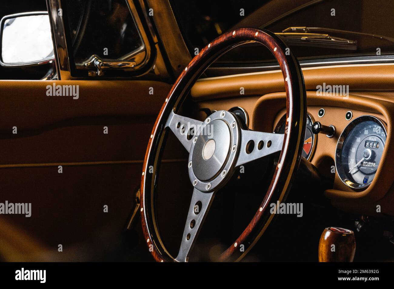 Volante in legno e acciaio in cabriolet di lusso retrò con interni in pelle beige parcheggiato in garage Foto Stock