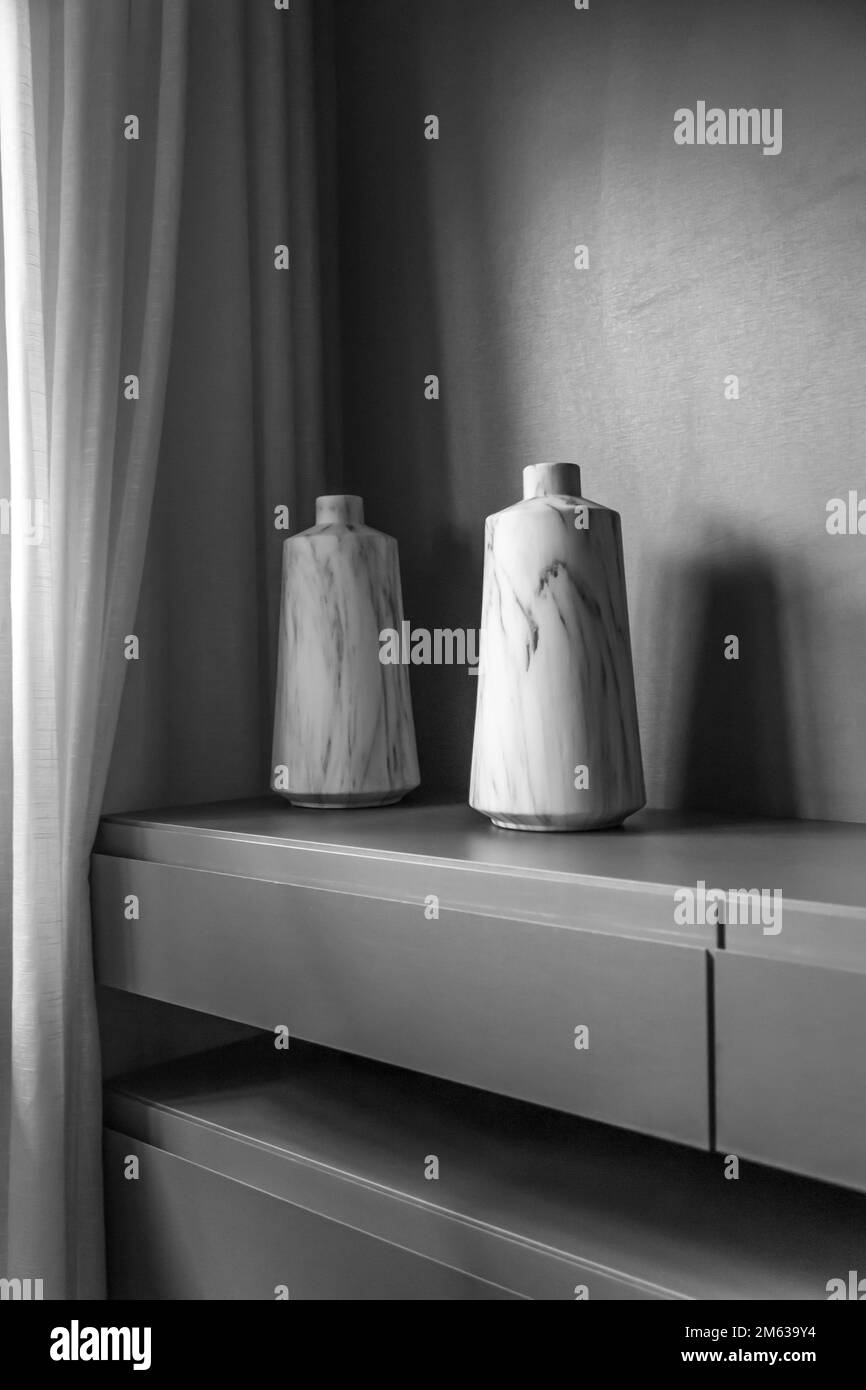 Coppia di vasi in marmo bianco e nero posizionati sulla parte superiore del moderno armadio vicino alla tenda a casa. Foto Stock