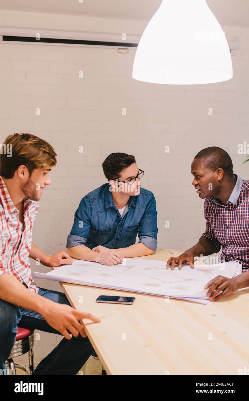 Architetti e ingegneri che lavorano in ufficio seduti in un grande tavolo Foto Stock