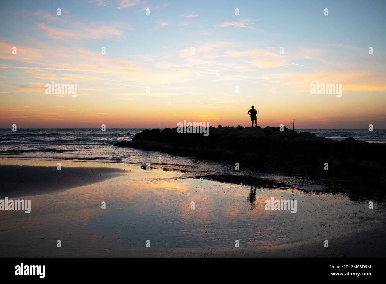 L'uomo rilassato osserva il mare dalle rocce Foto Stock