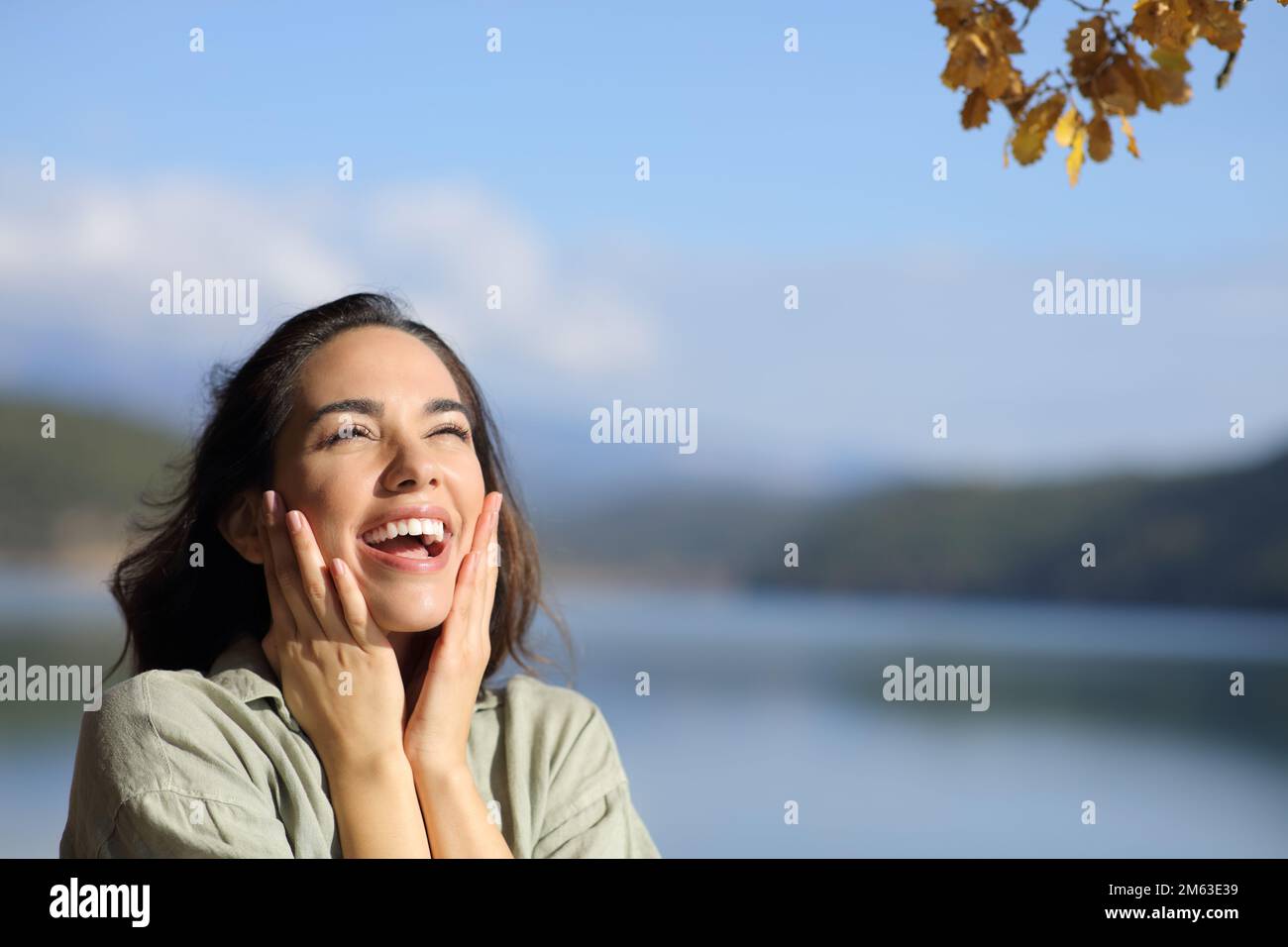 Sorpresa felice donna guardando sopra in un lago in vacanza con spazio copia Foto Stock