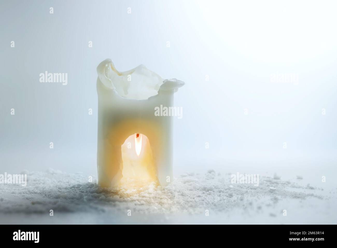 La candela bianca sta bruciando capovolto in un'incisione, calore di risparmio e concetto di energia, vita ferma surreale di festa di inverno, fondo grigio chiaro, spazio della copia, Foto Stock