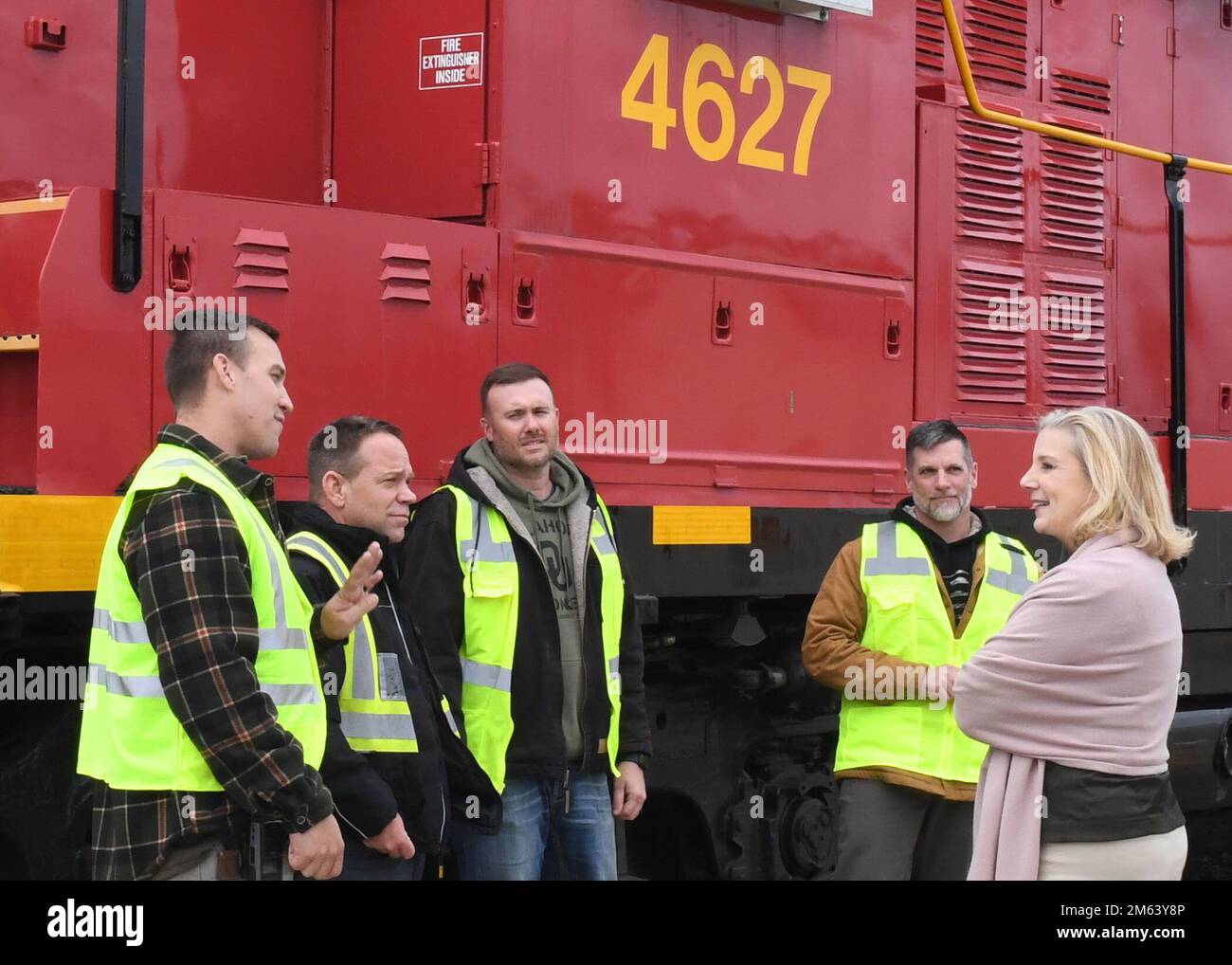 Locomotive Braker/Switcher Bret Parent (a sinistra) spiega che è un dipendente di quarta generazione MCAAP al Segretario dell'Esercito Christine Wormuth durante il suo tour di MCAAP marzo 22. Il principale civile dell'esercito ha ringraziato il team delle operazioni ferroviarie composto da quattro persone per la loro rapida risposta e per il supporto di una recente missione a Fort Carson, Colorado. Accanto a Parent c'è suo padre, l'ingegnere locomotore Loman "Moose" Parent, Braker/Switcher John Duke, e il direttore Randall Cate. Foto Stock