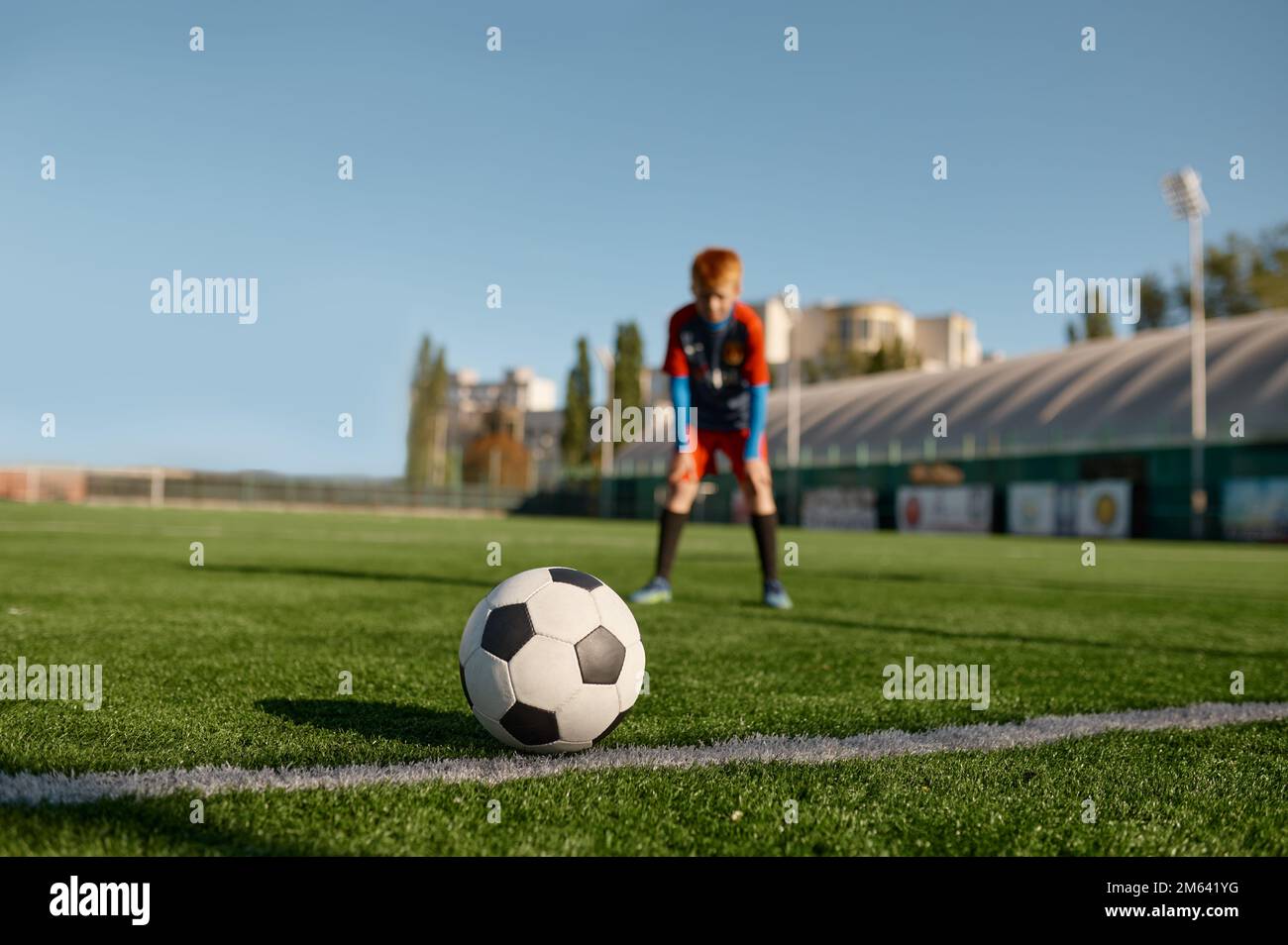 Ragazzo giocatore di calcio che guarda il pallone da calcio prima di calciare Foto Stock