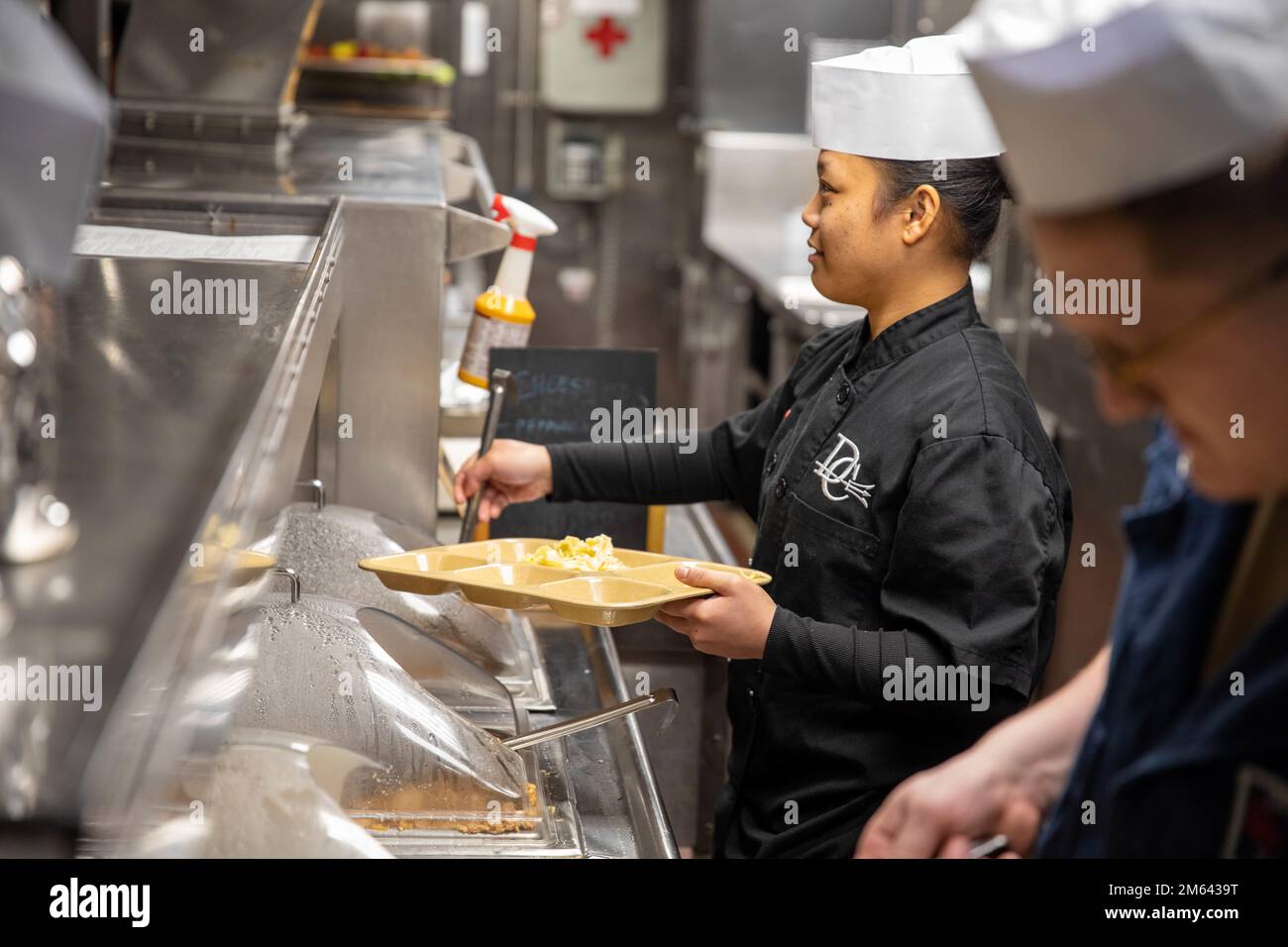 MAR BALTICO (30 marzo 2022) – lo specialista culinario Seaman Alyssa Cuntapay serve la cena all'equipaggio nella cucina del cacciatorpediniere missilistico guidato della classe Arleigh Burke USS Donald Cook (DDG 75), marzo 30. Donald Cook è schierato al Teatro europeo delle operazioni e partecipa a una serie di attività marittime a sostegno degli Stati Uniti Sesta flotta e alleati della NATO. Foto Stock