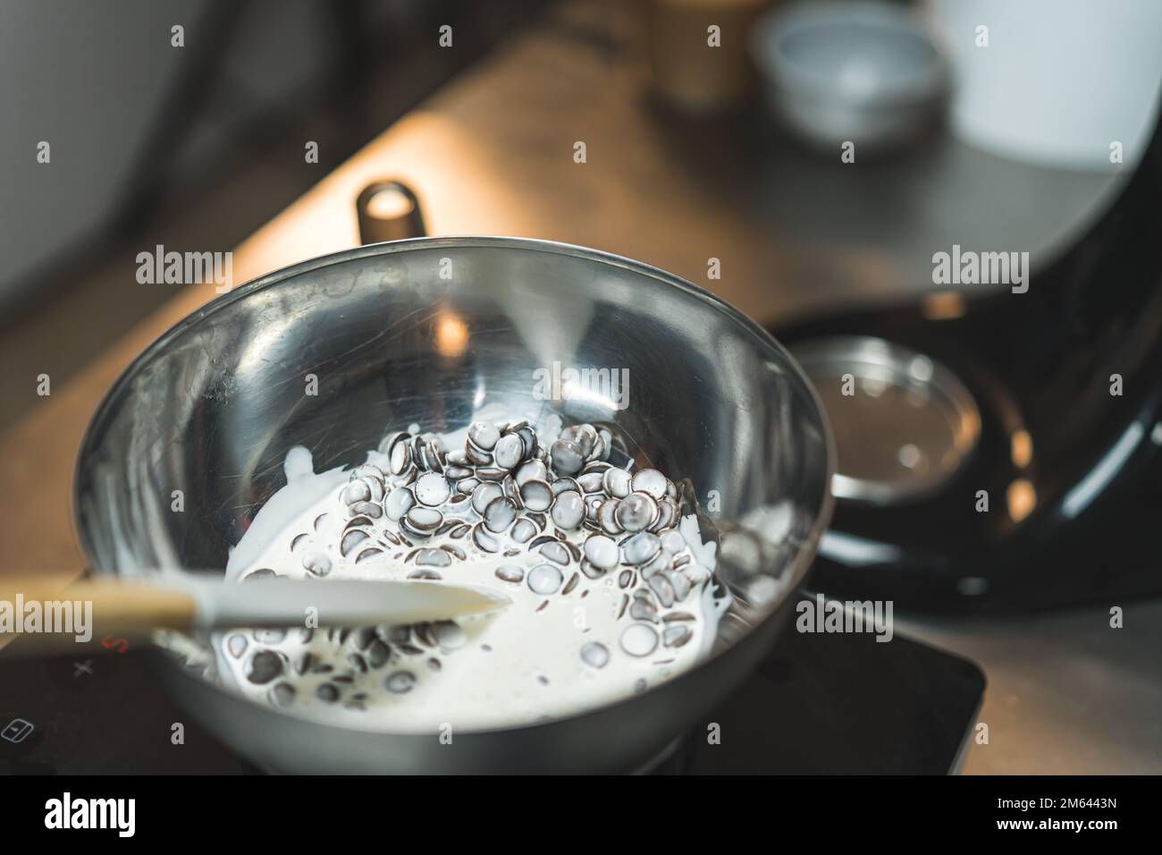 Colpo di primo piano di gocce di cioccolato fondenti con panna pesante su acqua bollente. Sfondo sfocato. Foto di alta qualità Foto Stock