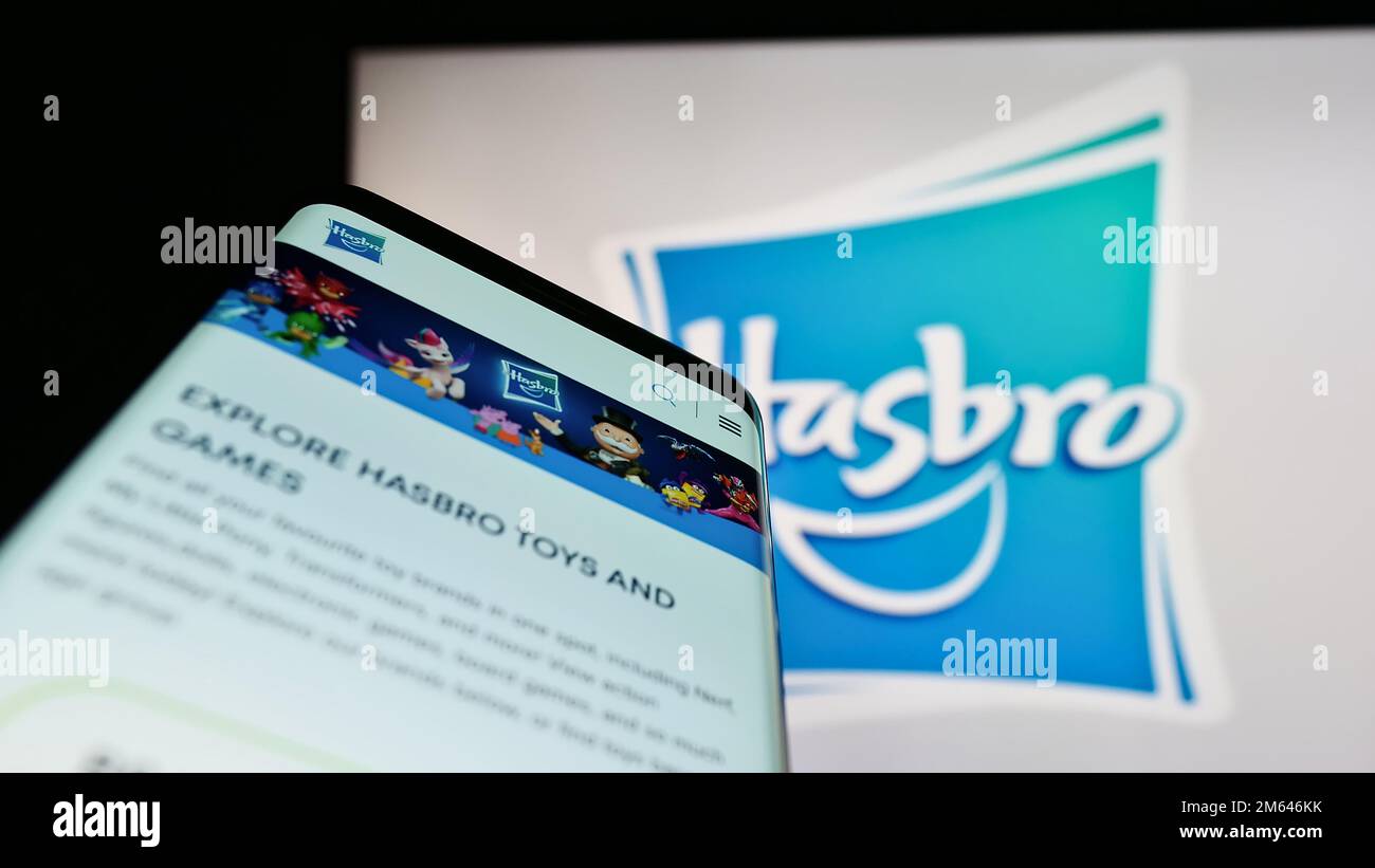 Telefono cellulare con pagina web della società americana di giocattoli e intrattenimento Hasbro Inc. Sullo schermo di fronte al logo. Messa a fuoco in alto a sinistra del display del telefono. Foto Stock